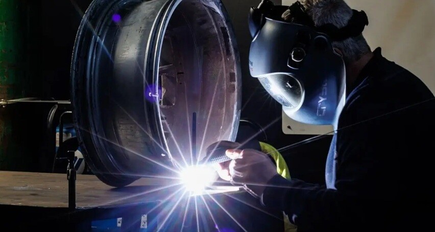 a welding man repairing a mechanical part in a dark room