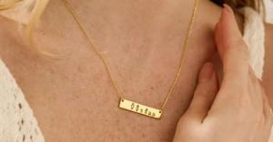 a bar necklace with a print of family members worn round a lady's neck