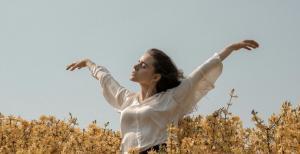 a lady keeping her hands high on an open environment with blue sky