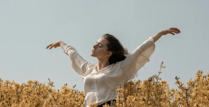 a lady keeping her hands high on an open environment with blue sky