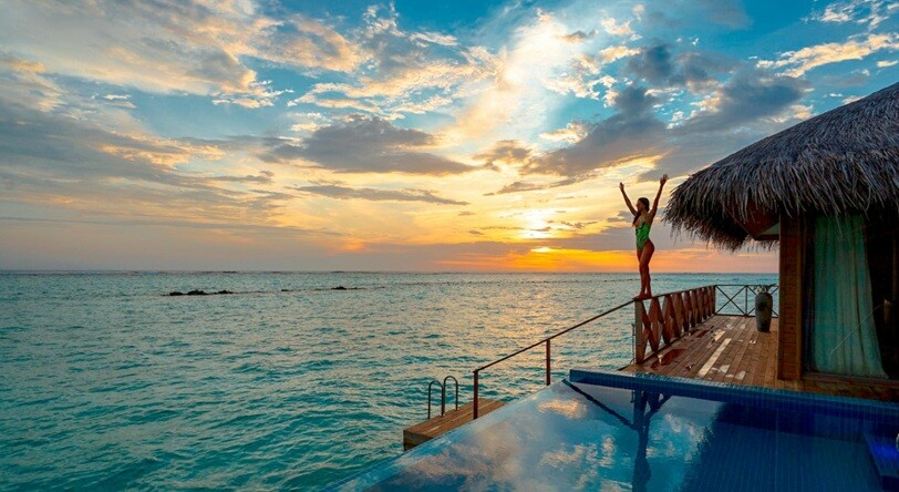 a resort place with blue water and sunset and a lady enjoying the climate