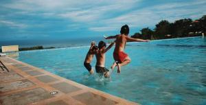 three kids jumping into a swimming pool in an evening sunset