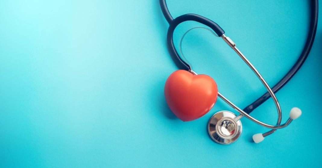 On a blue background sits a stethoscope and a red heart, both situated to the right of the photo.