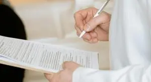 a doctor holding a pen and writing something on a notepad
