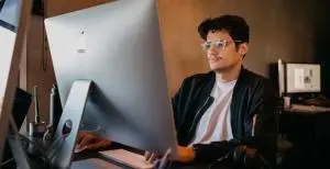 a professional working on a laptop sitting on a char with glasses