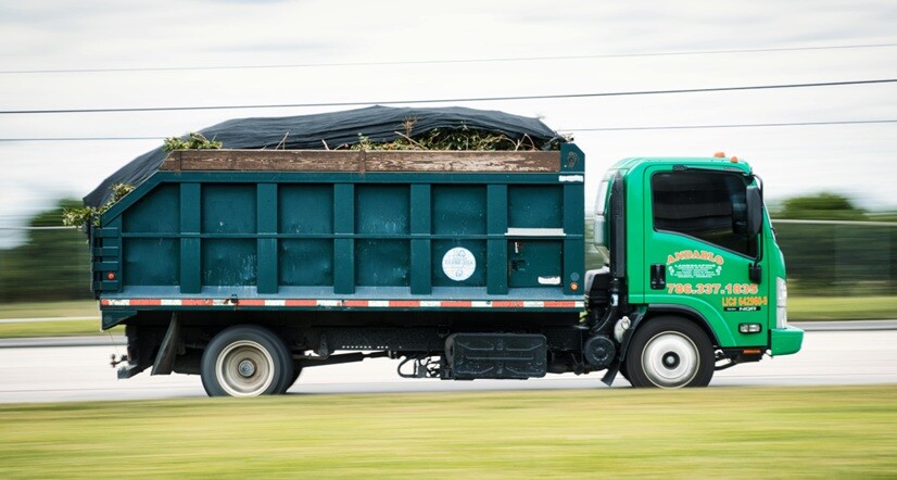a truck seen on the road taking yard wate in a clear day time