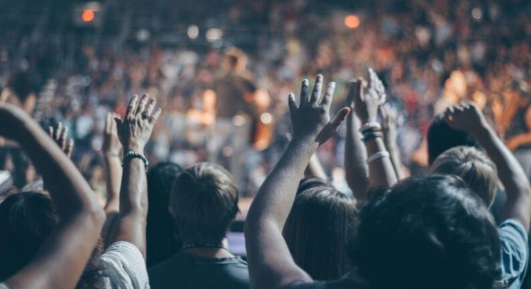 people applauding with their hands facing a stage performance