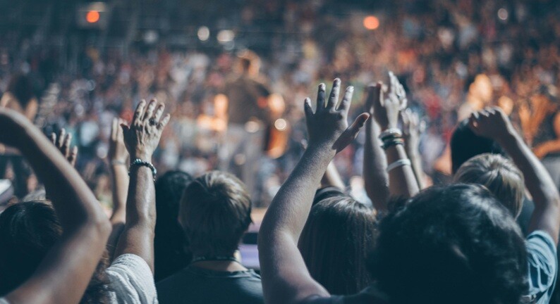 people applauding with their hands facing a stage performance