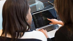 two ladies discussing on a laptop about salesforce software