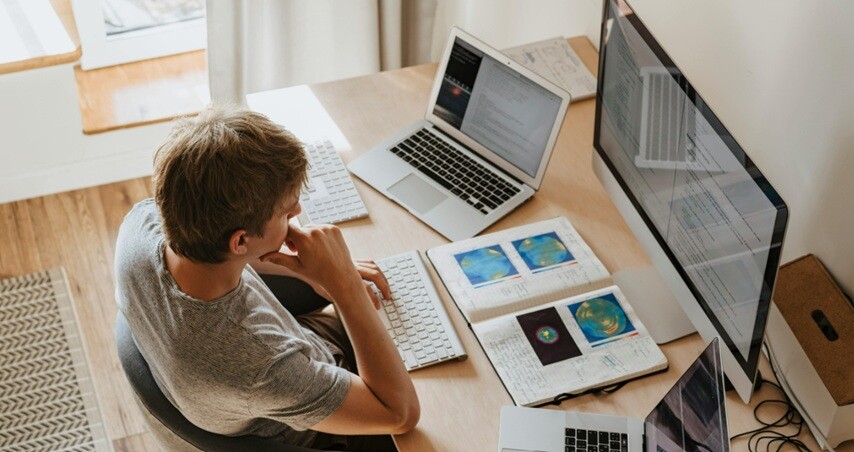 ERP software being worked by a person with his desktop and two laptops