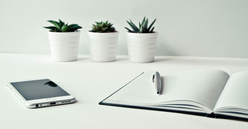 innovation a book, pen, tab and three pots placed on a table