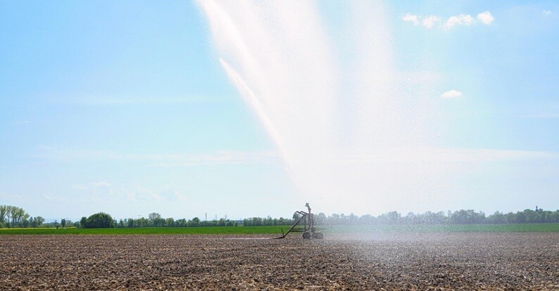 agricultural land with water being sprinkled over the land areas wit a clear blue sky background