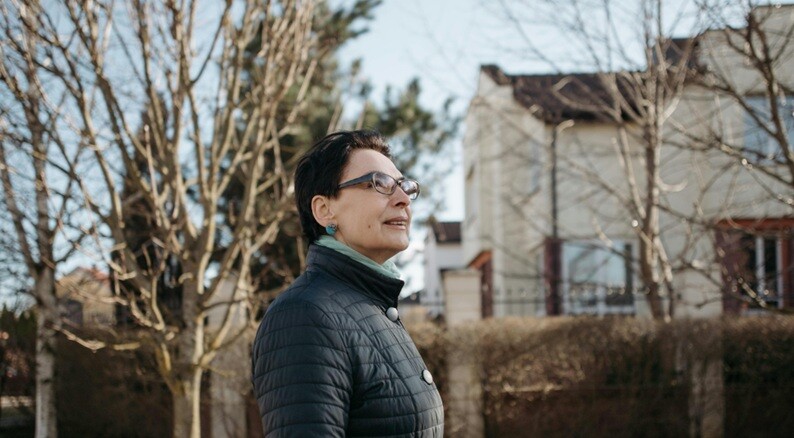 residence a lady standing near a residential building with a tree beside it