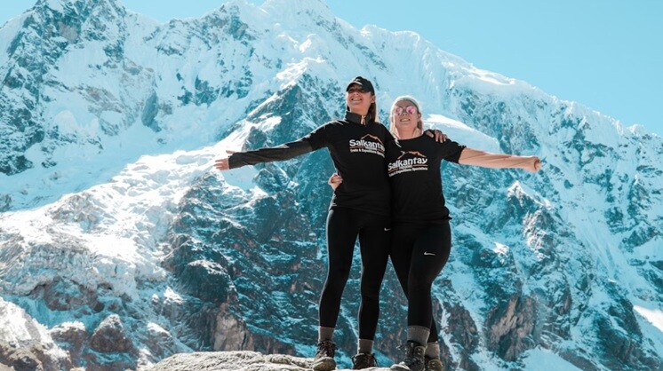 tour two ladies standing holding hands each other in the mountain top with snow
