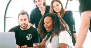 a group of people looking at a laptop creatively and attentively