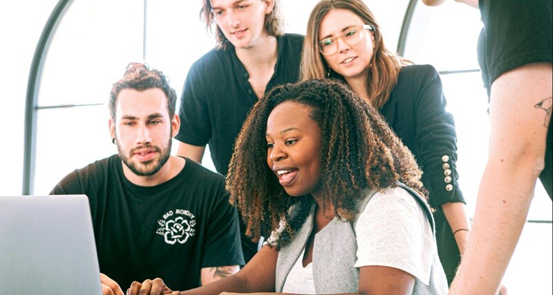 a group of people looking at a laptop creatively and attentively