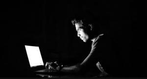 a person using his laptop to hack the system in a black background