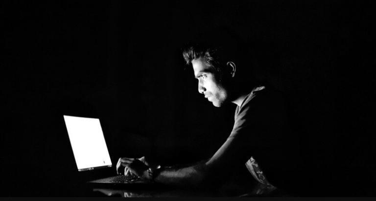 a person using his laptop to hack the system in a black background
