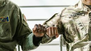two military persons in uniforms hold hands each other