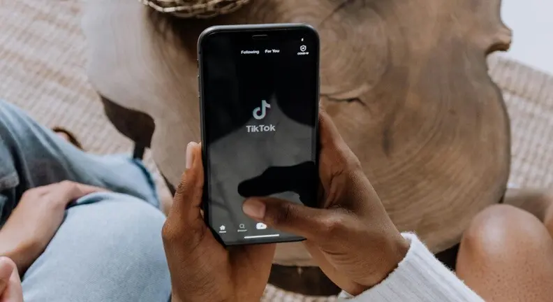 a person holding a hand with a mobile with tik tok displayed