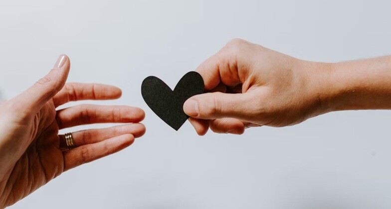 a man gives a heart symbol to an elderly lady with gray background