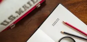 a notepad seen open and two pencils placed on a table