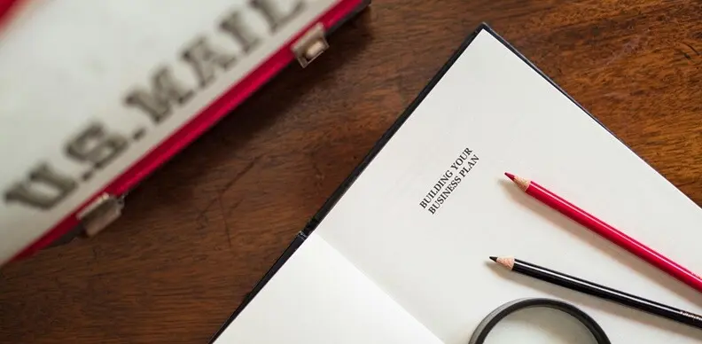 a notepad seen open and two pencils placed on a table