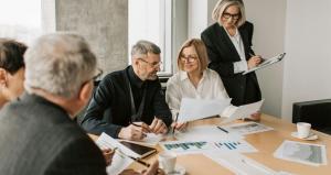 a group of people discussing and consulting with charts and papers in office