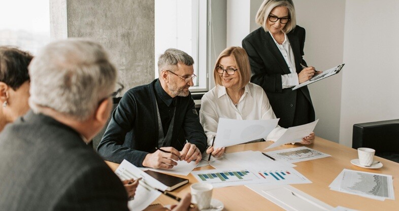 a group of people discussing and consulting with charts and papers in office