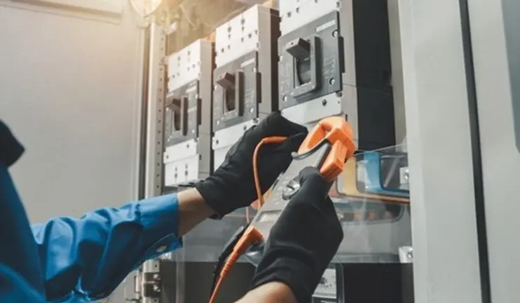 electrician working on a panel with meters and wires