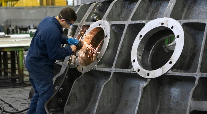 a workman welding on a huge equipment in a factory