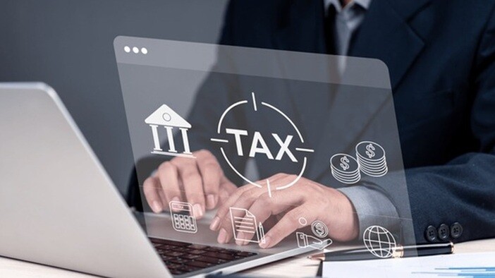 the word tax displayed on a glass screen with a person in the behind