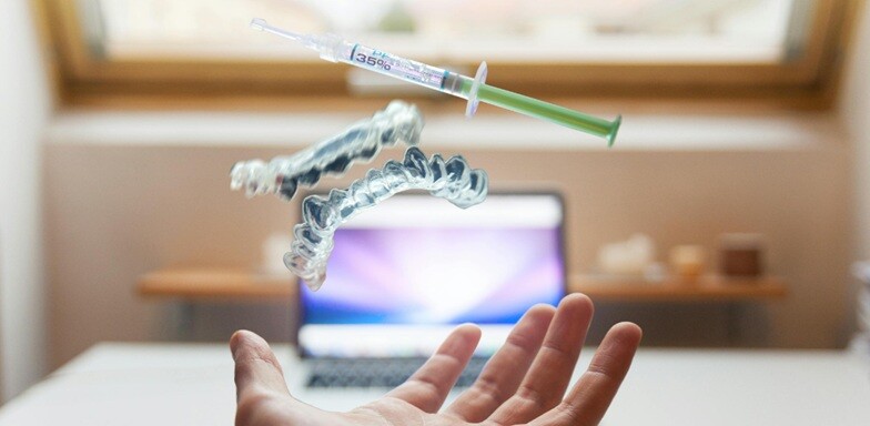 aligners dental aligner with syringe and a human hand with a laptop in background