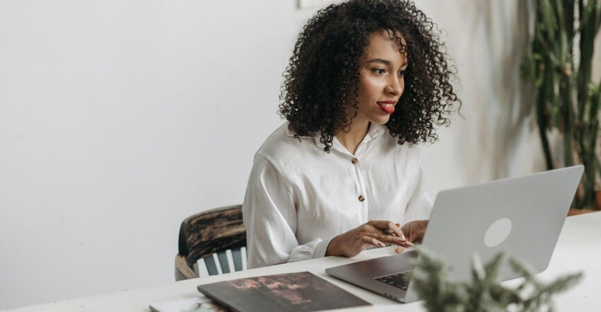 a lady working on a laptop with books and papers with remote assistance