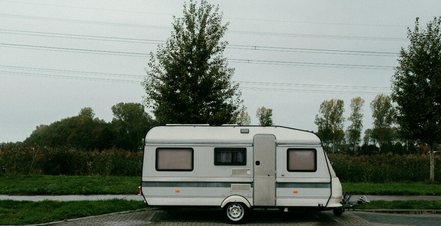a motor home seen parked on a road with trees beside it