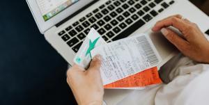 a person holding receipts, card and bills for feeding into the laptop