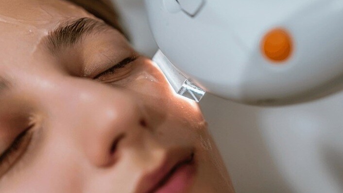 a lady undergoing facial treatment with a device
