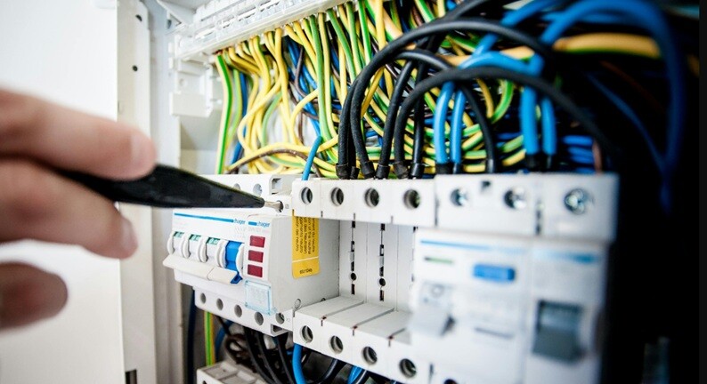 an electrical control box with a lot of wires and connectors being repaired by an electrician