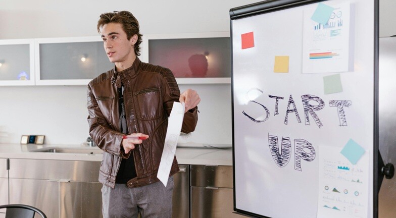 start up a person standing and explaining his startup on a white board