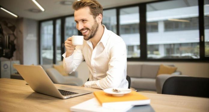CRM executive drinking coffee sitting in front of the laptop with books