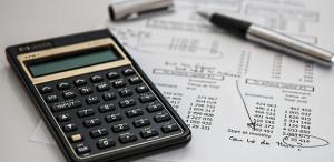 a calculator, paper with financial statements seen lying on the table