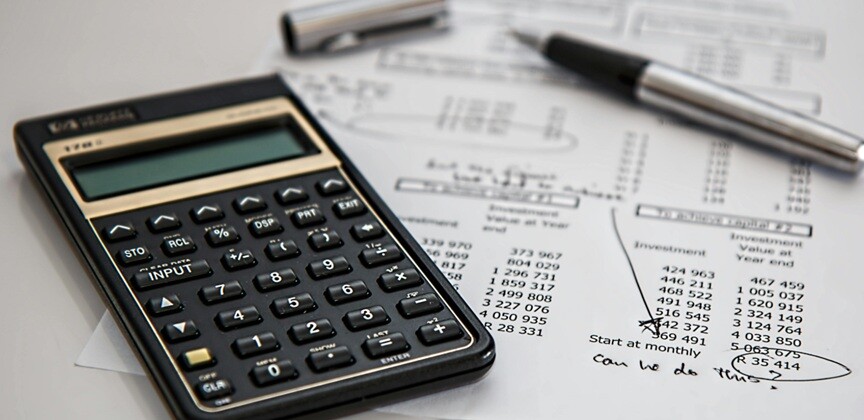 a calculator, paper with financial statements seen lying on the table