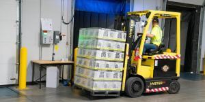 a stacker being operated by a person moving packets of goods