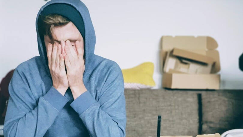a person holding us hand on his face with stress sitting on a sofa