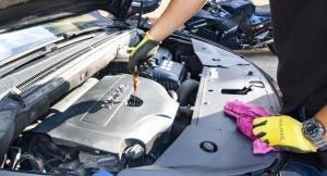 a mechanic repairing a car engine wearing a glove on the bonnet