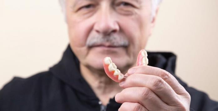a person holding a denture in his hand who is wearing black t-shirt